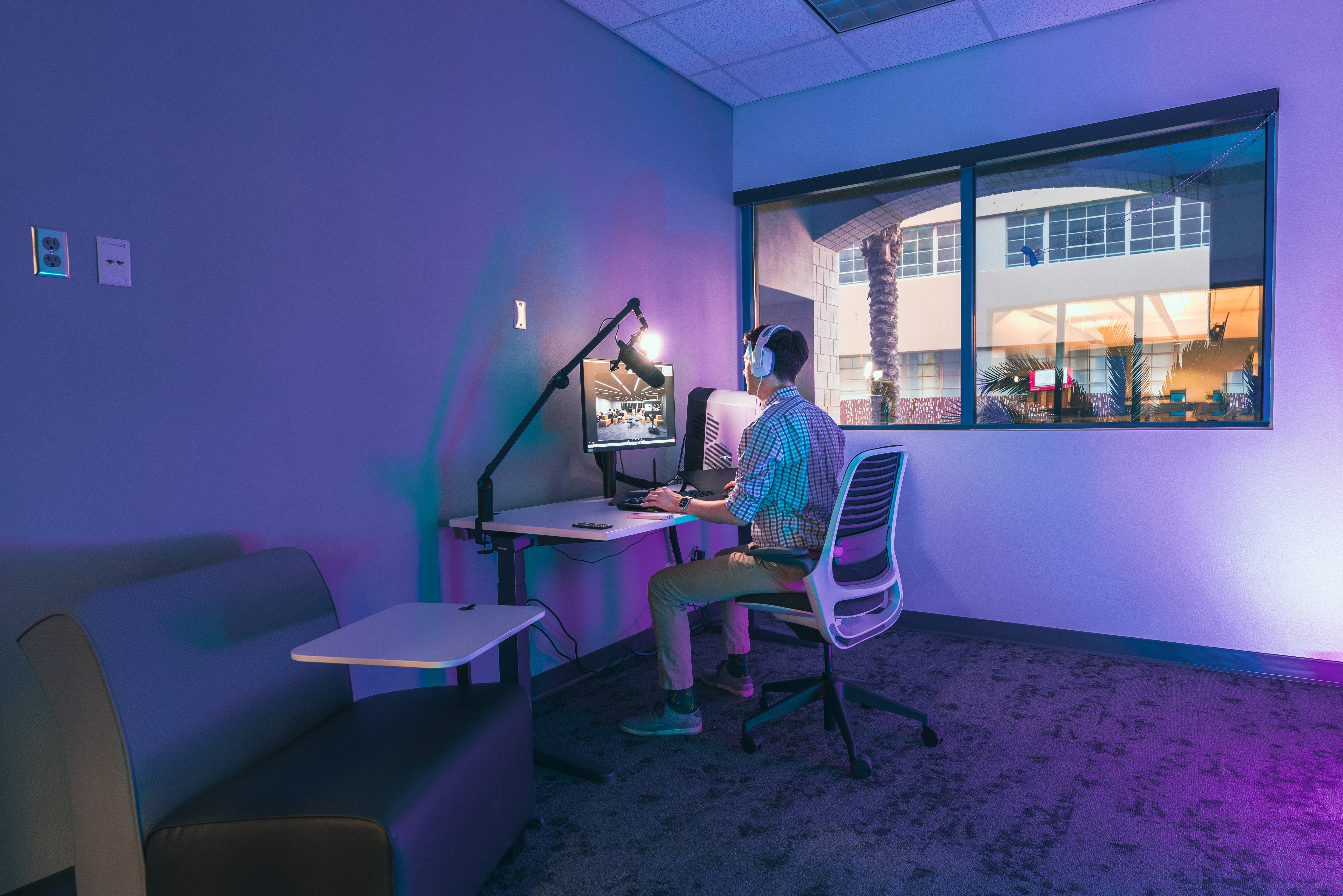 Student sitting at a desk in a room with purple lighting