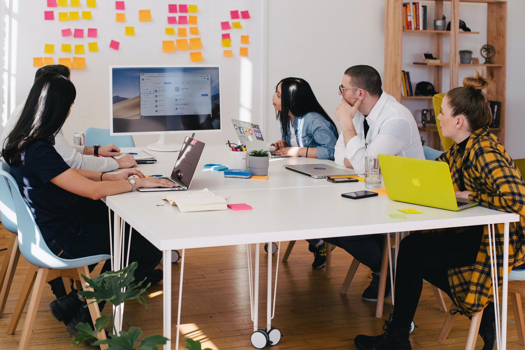 Individuals looking at a screen together and taking detailed sticky-notes.