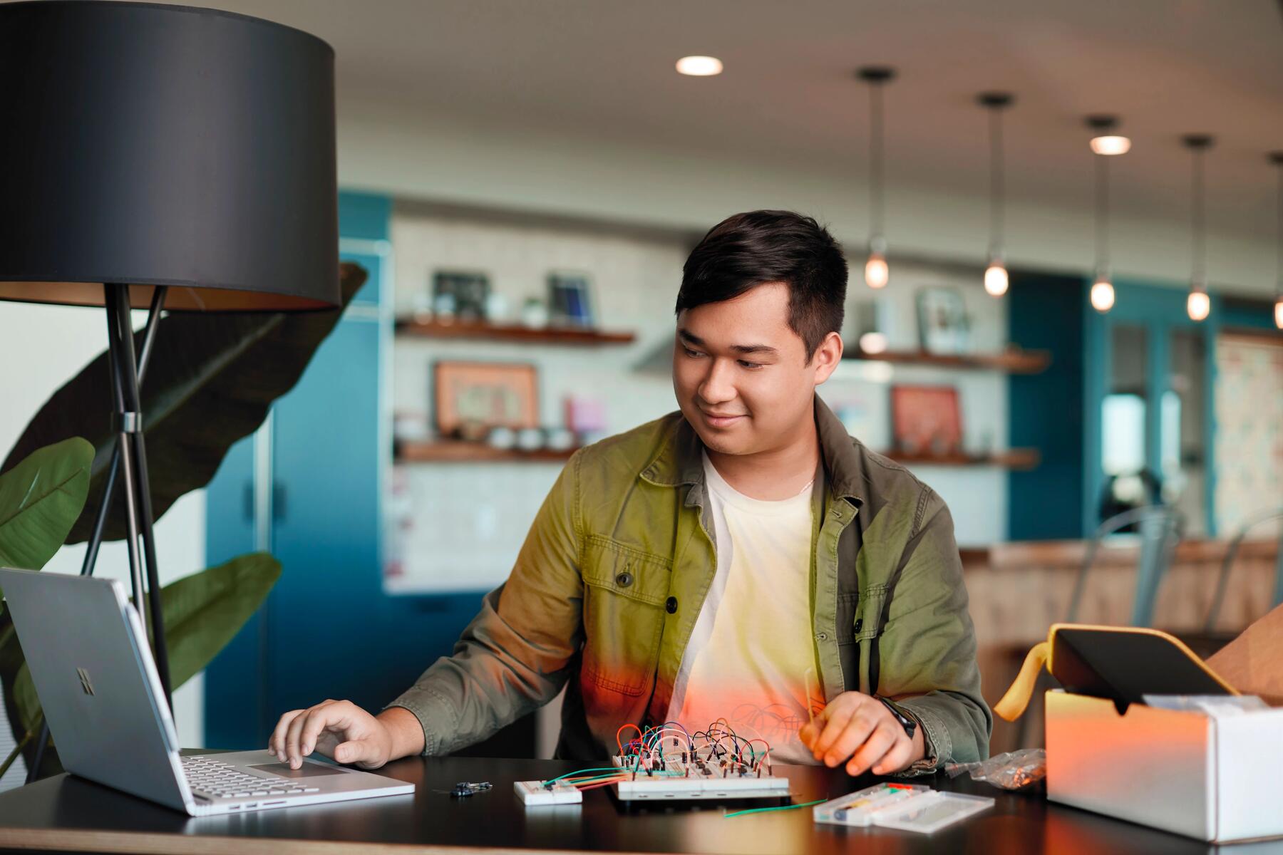 Man reading his computer and fiddling with computer wires.