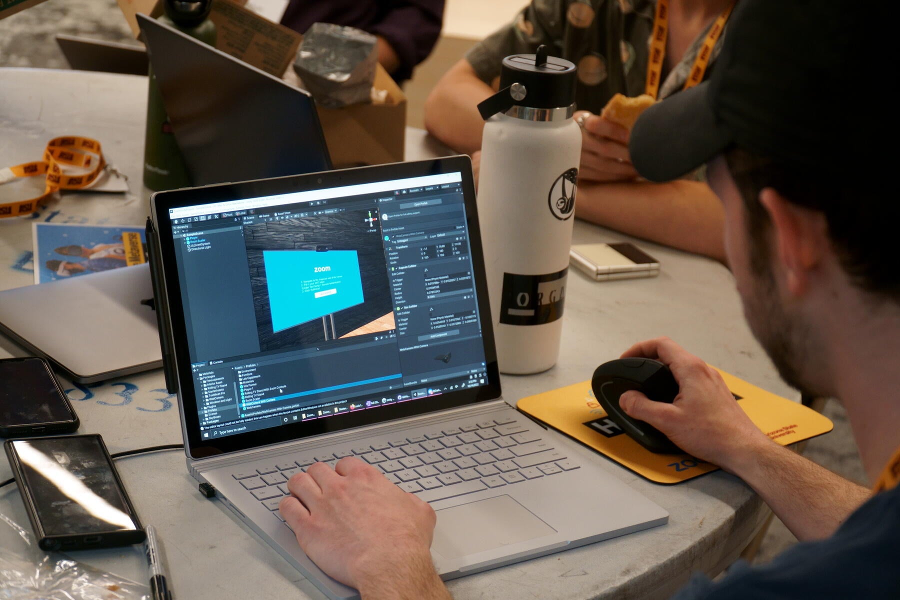 Open laptop screen with student sitting down at table. 