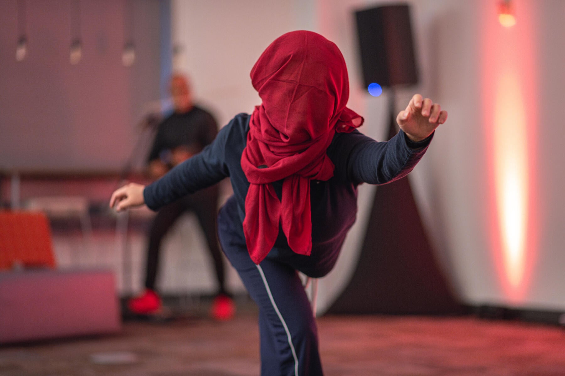 Performer dancing and holding a pose with a red scarf covering her face
