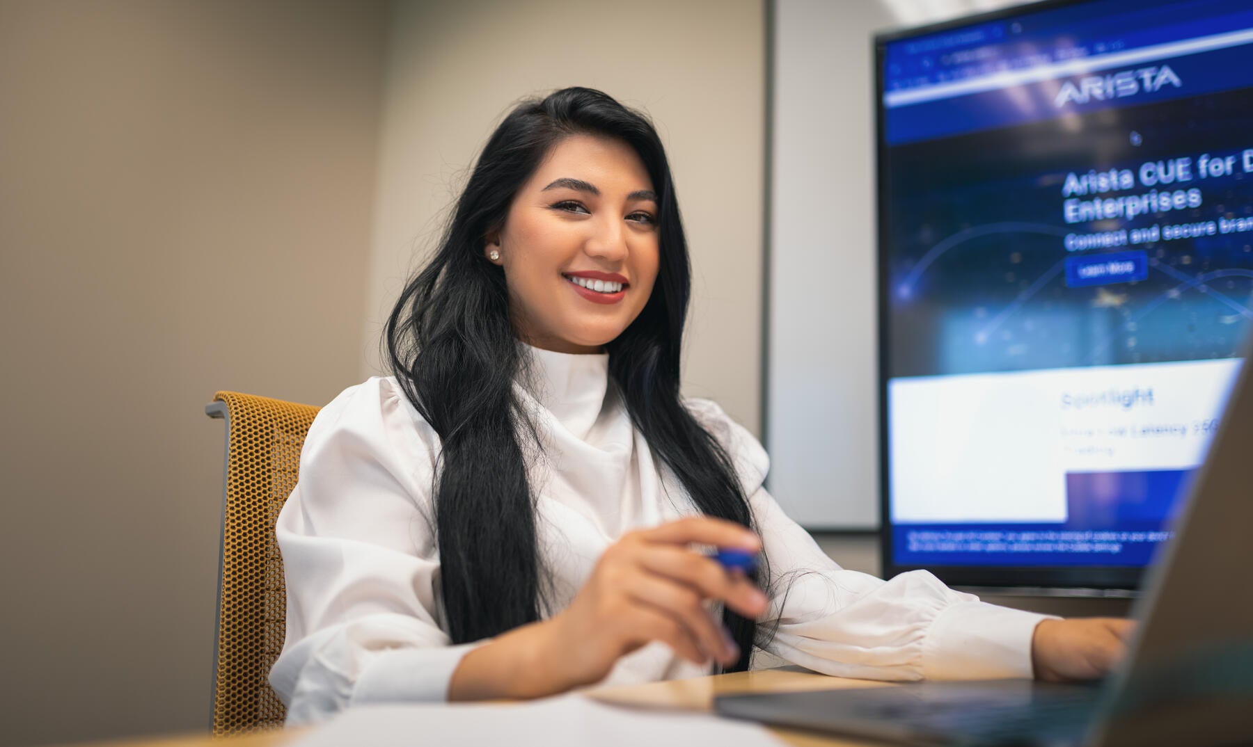 Woman sitting at desk in white shirt with laptop