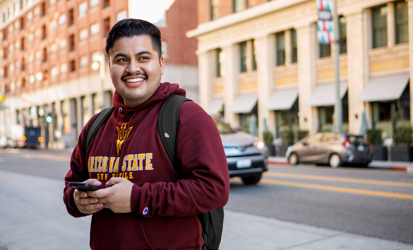 Male student smiling and holding cell phone