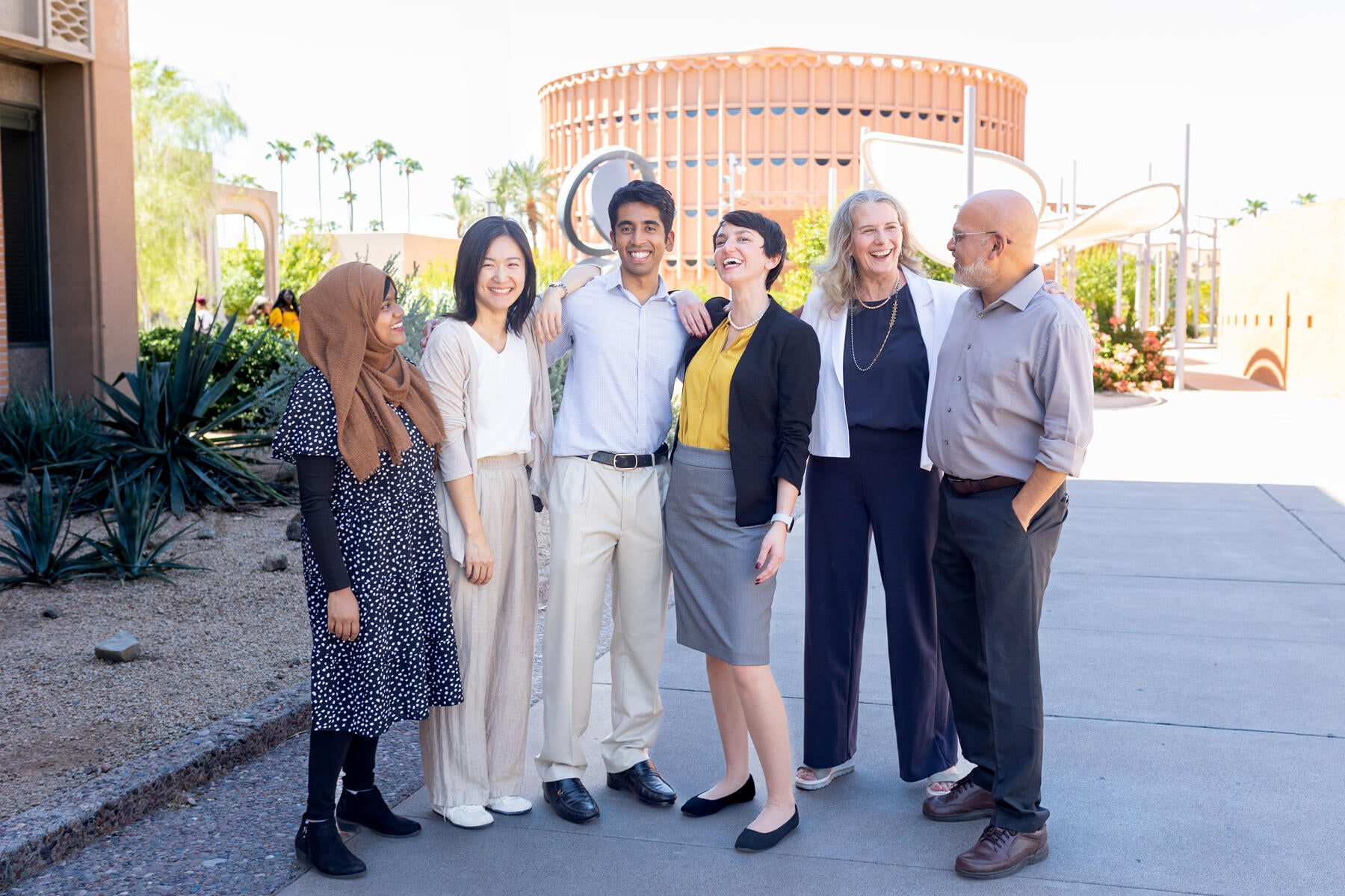 A group of six staff members standing and laughing with each other