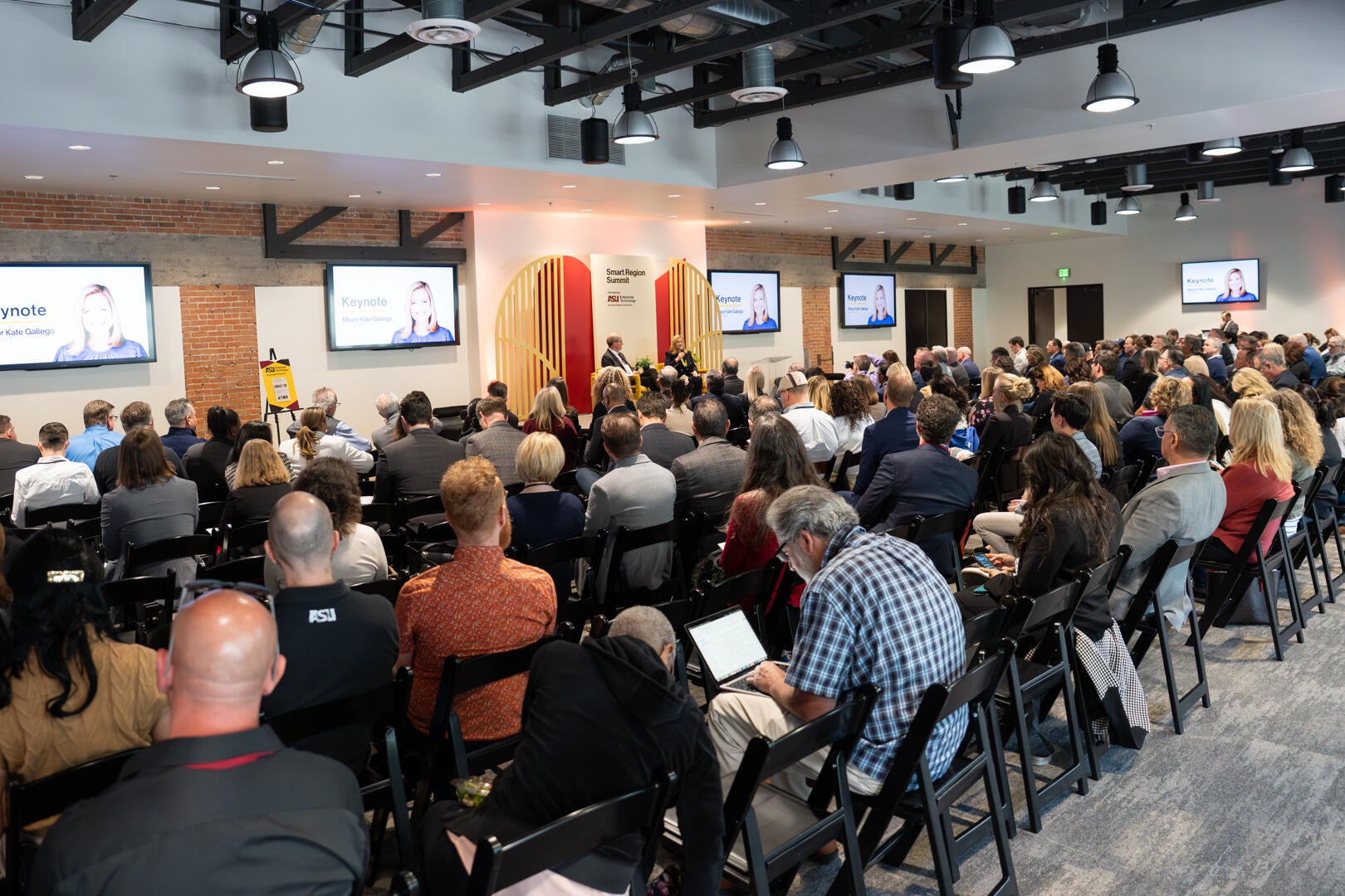 A gathering of 250 people seated in a large room with a stage at the front