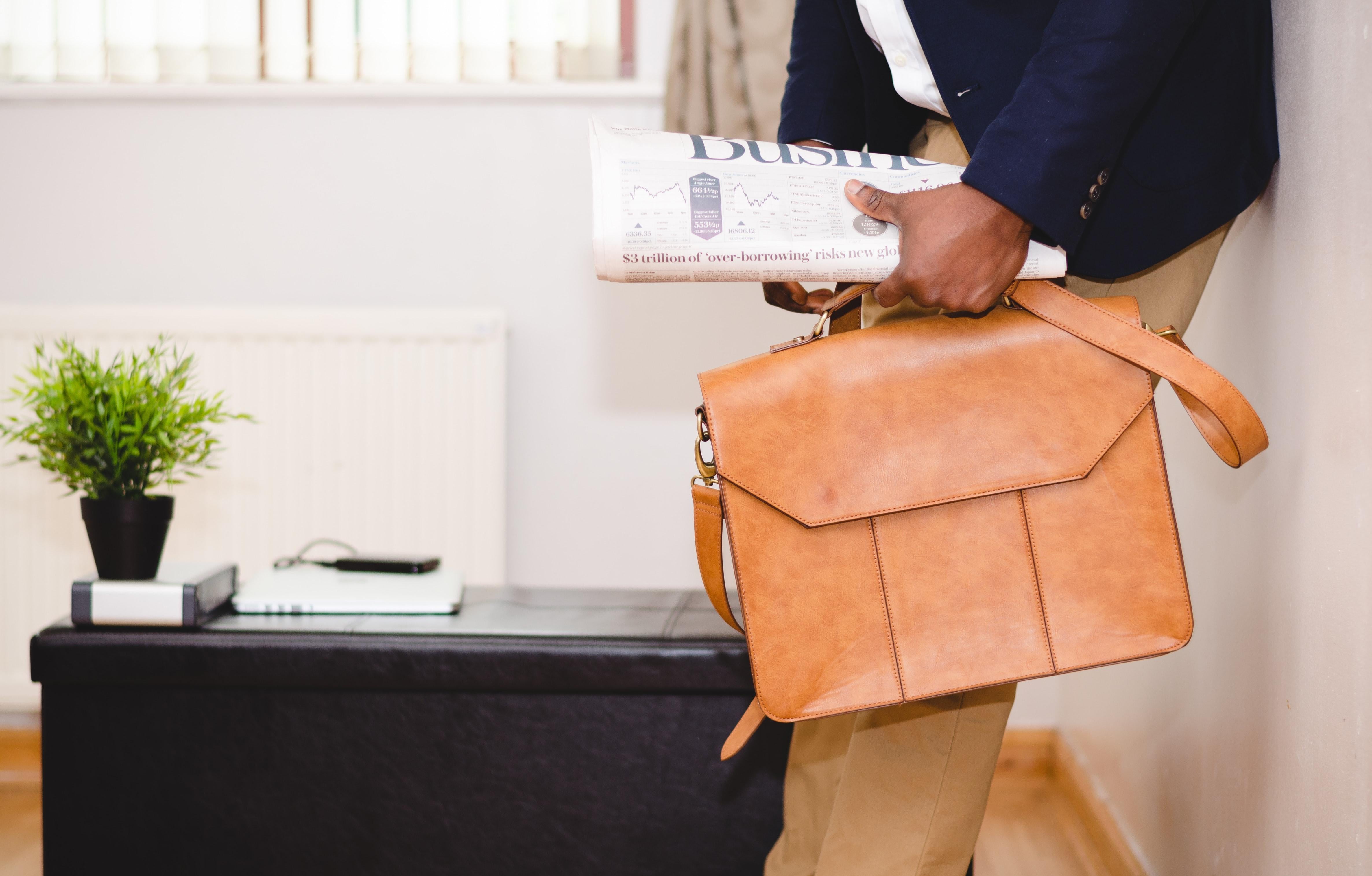 Man holding a newspaper and briefcase