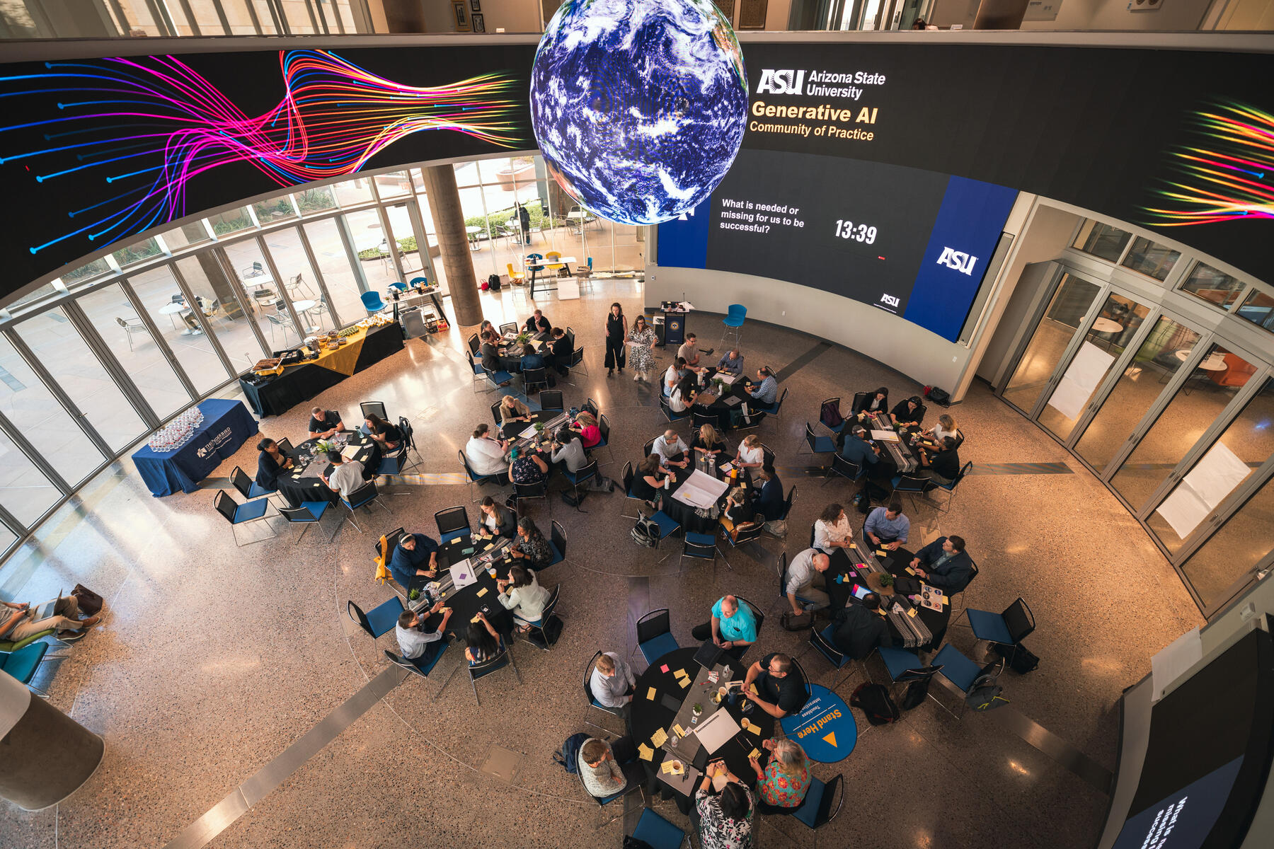 Birds eye view of a room with tables of groups sitting and working together.