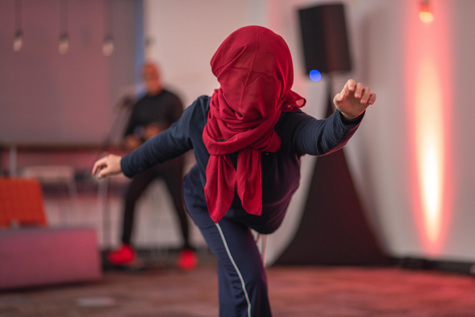 Performer dancing and holding a pose with a red scarf covering her face