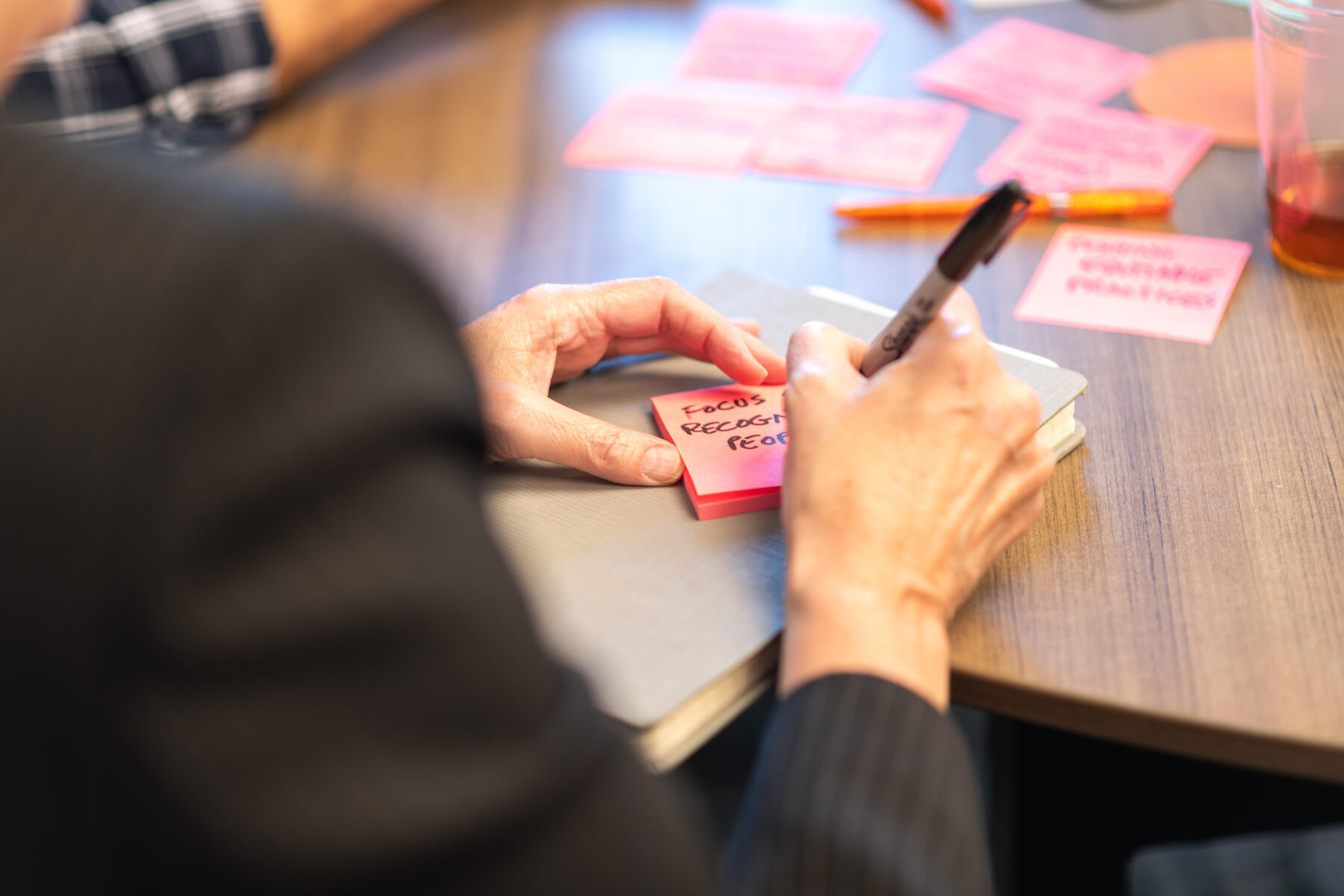 Hand writing on a pink sticky note