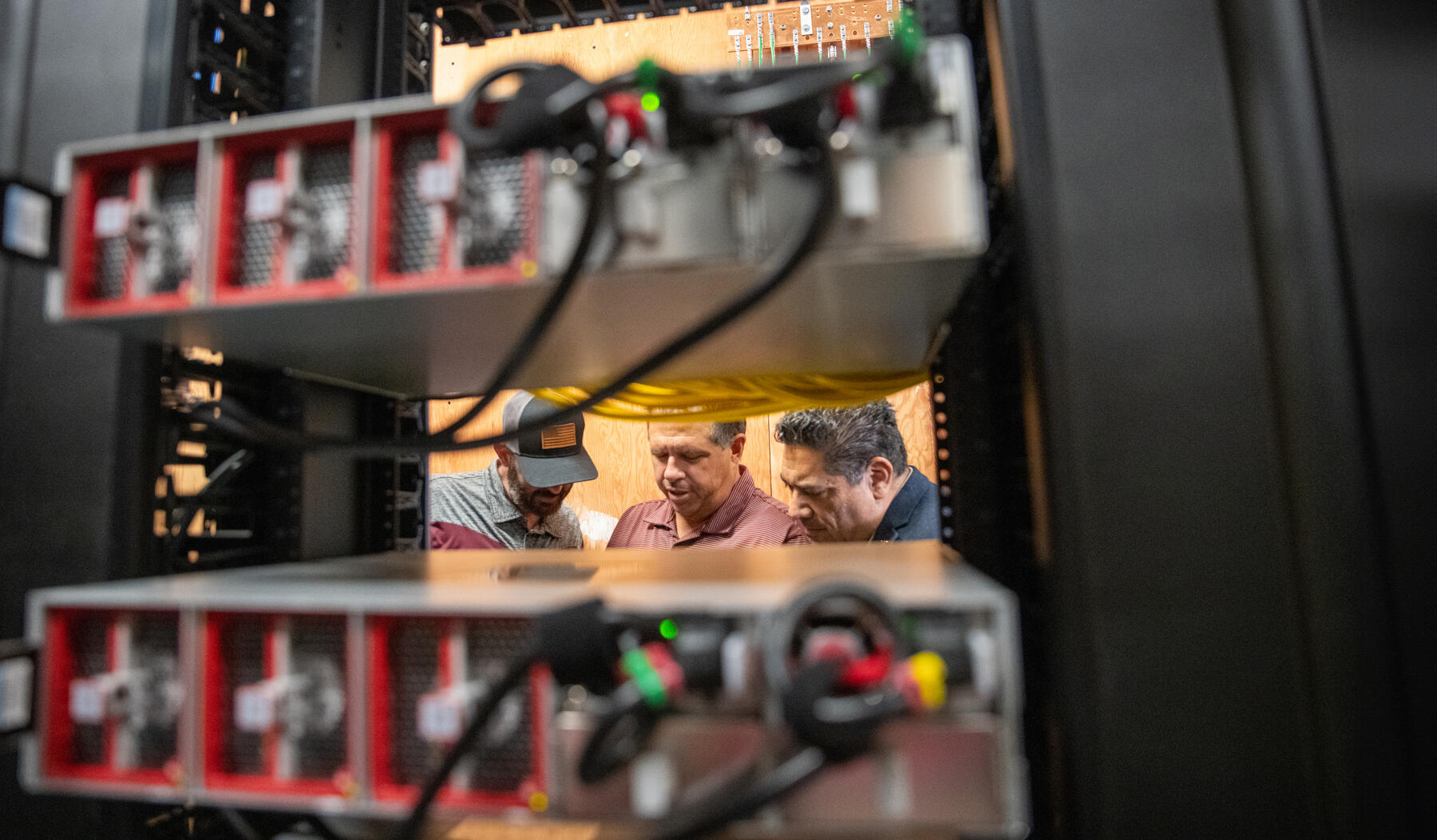 Three men working inside a network center