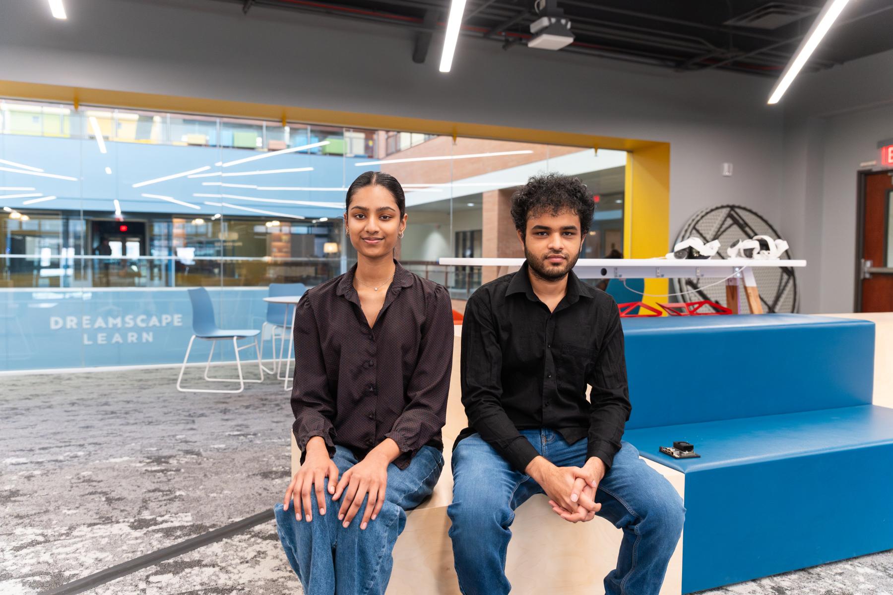 Two students seated on a blue couch 