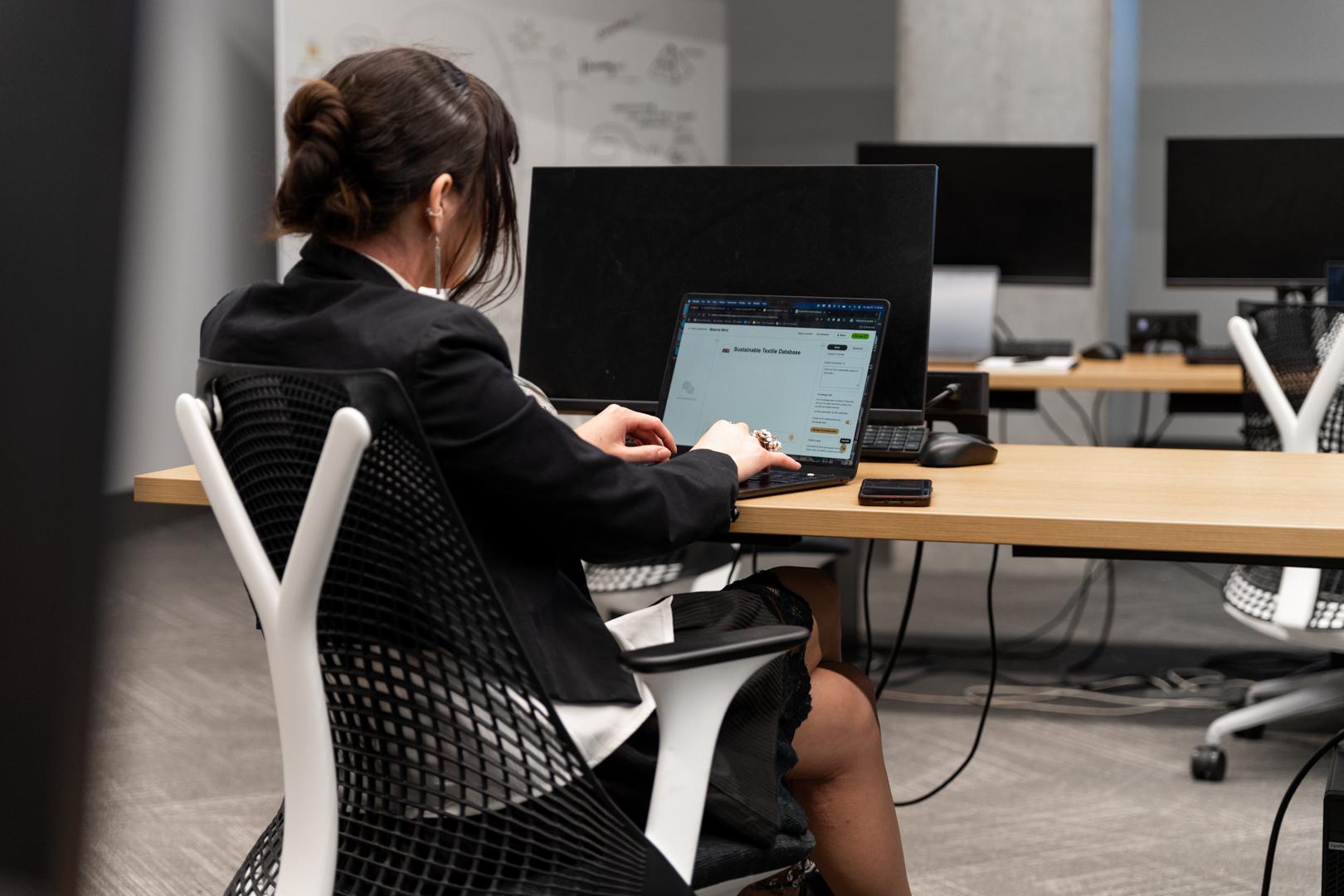 A student is seated at a desk working on their laptop