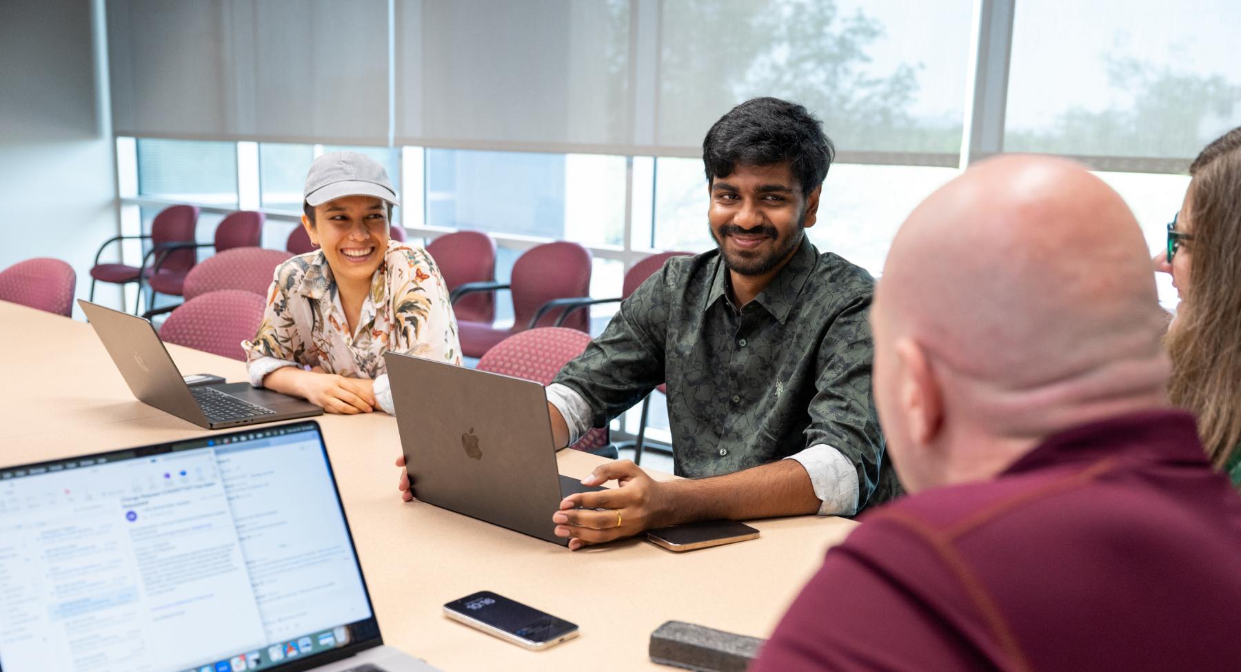 Two students at a desk with their laptops